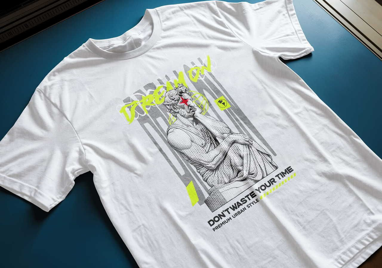 White t-shirt on a blue surface with a graphic of a classical statue and neon accents. Text: "Dream On" and "Don't Waste Your Time".