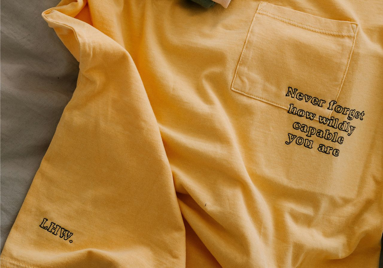 Yellow fabric with a pocket bears the text, "Never forget how wildly capable you are." 