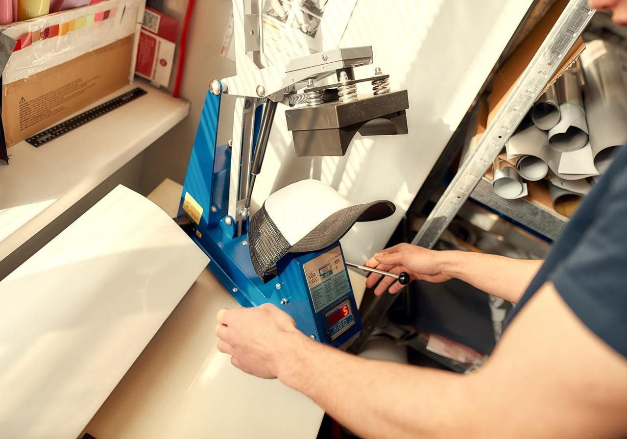 A man operates a machine to cut sheets of paper in a well-lit workspace.