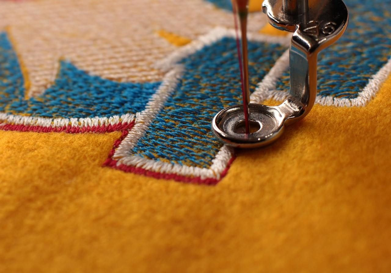 A sewing machine stitching a piece of fabric, with the needle moving up and down in a rhythmic motion.