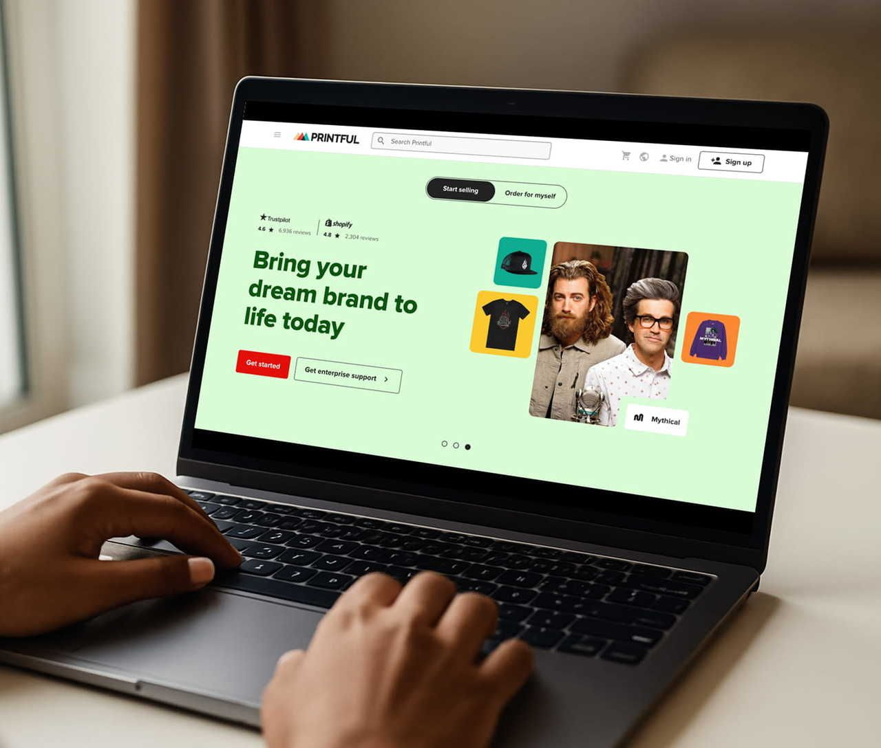 A person using a laptop with Printful’s homepage on the screen.