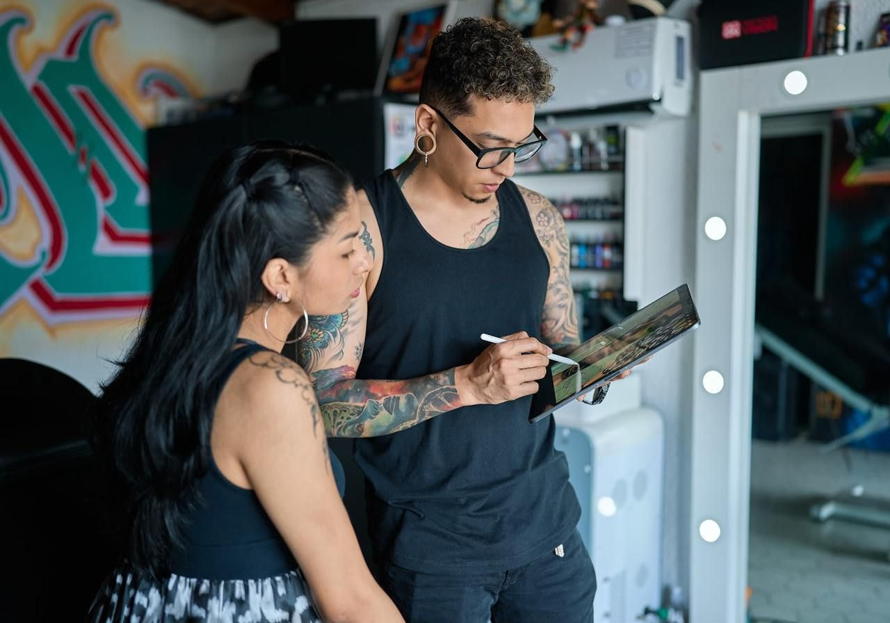A man and a woman are looking at a tablet in the man’s hands.