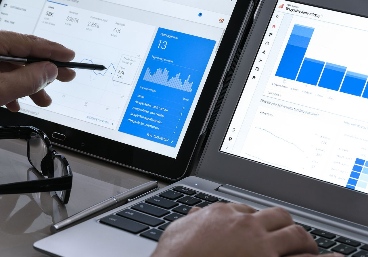 Two laptops display digital analytics with graphs and charts.