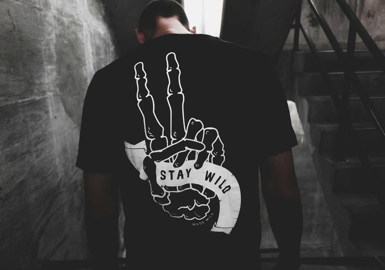 A backshot of man wearing a black “Stay wild” t-shirt