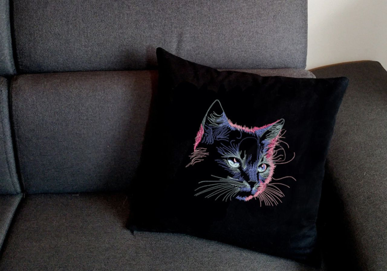 A black cat pillow featuring a vibrant, colorful design, adding a playful touch to home decor.