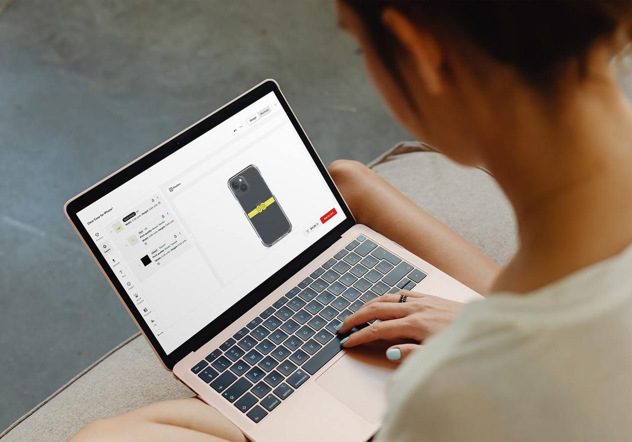 A person is using a laptop to learn how to make phone cases using Printful’s Design Maker.