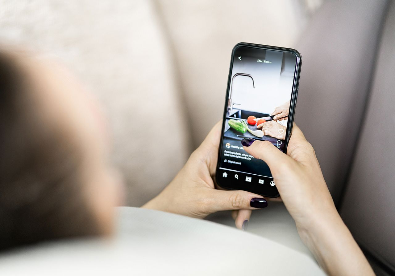 A woman holds her smartphone, capturing a photo with a focused expression on her face.
