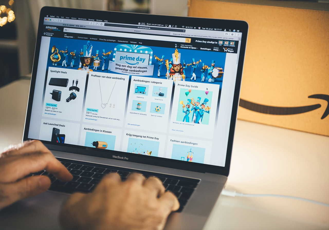 A person using a laptop to browse Amazon with various promotional offers displayed on the screen.
