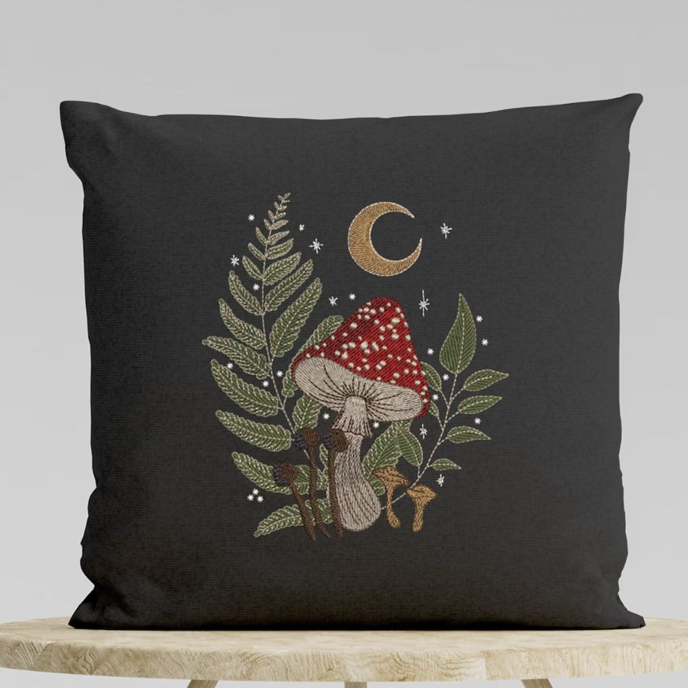A black cushion featuring a design of a mushroom surrounded by leaves.