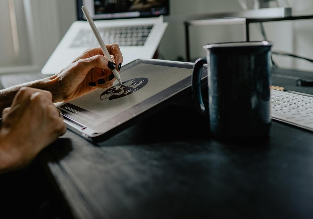A woman is using a tablet to create visual assets for personal branding.