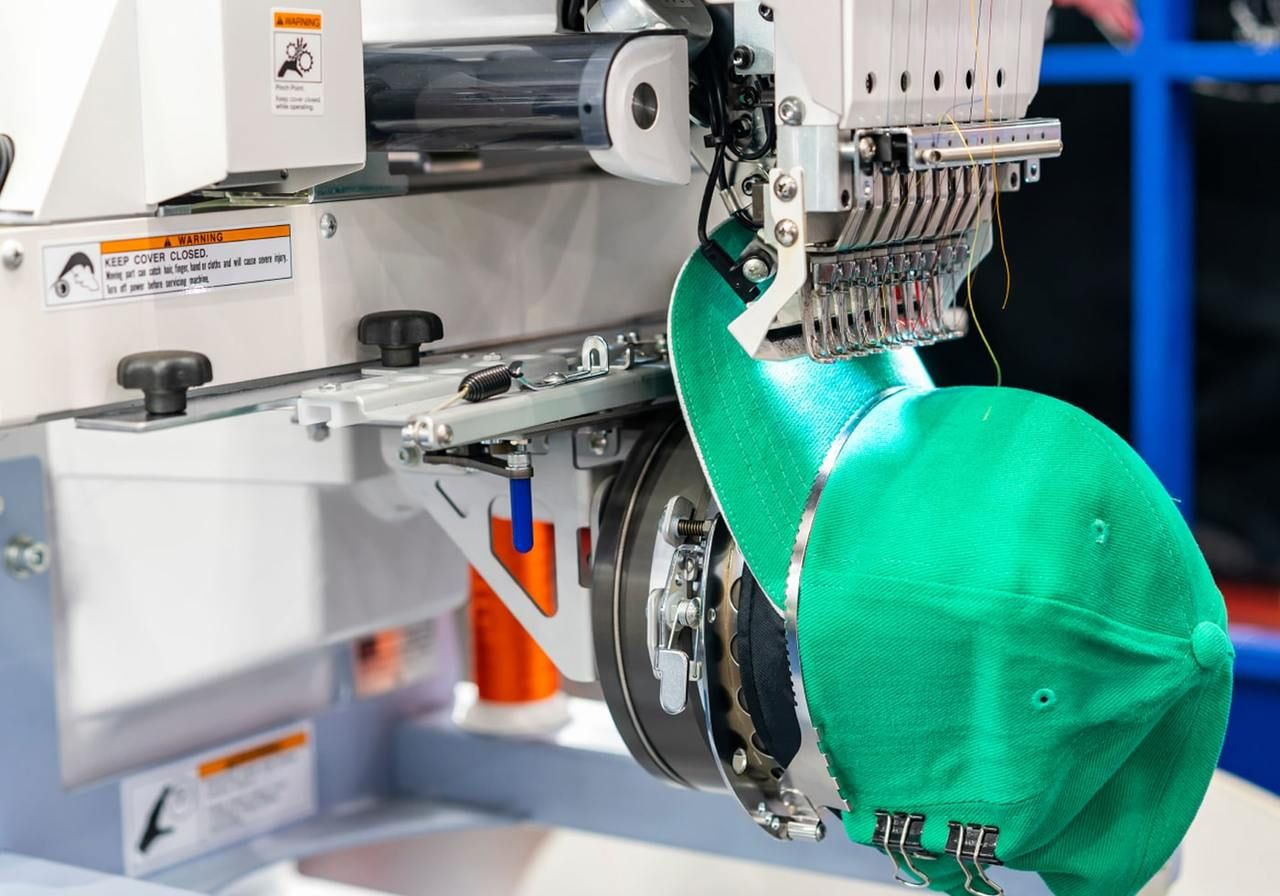 A person places a green hat onto a machine, highlighting the interaction between the object and the equipment.