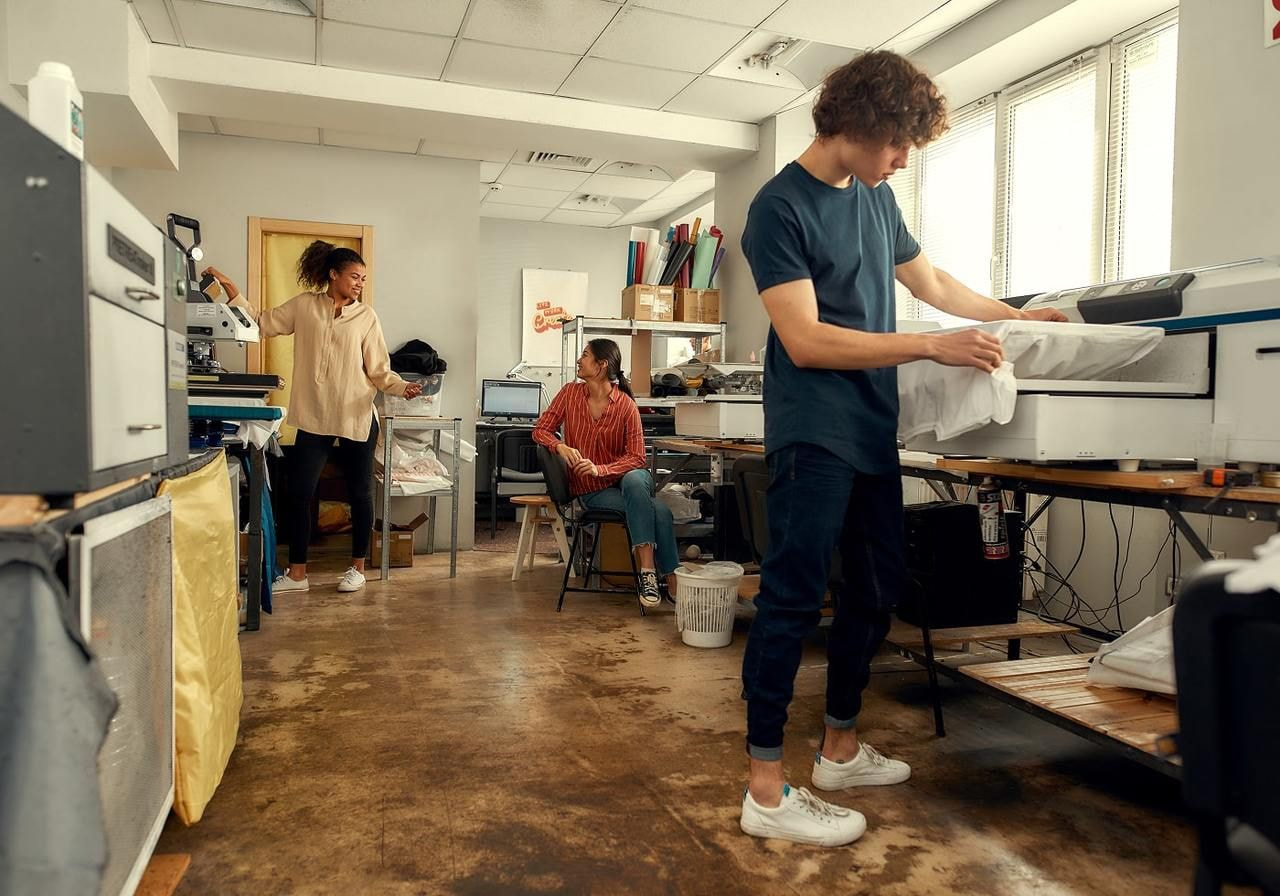 A man and woman collaborate on machinery in a factory setting, focused on their tasks amidst industrial equipment.