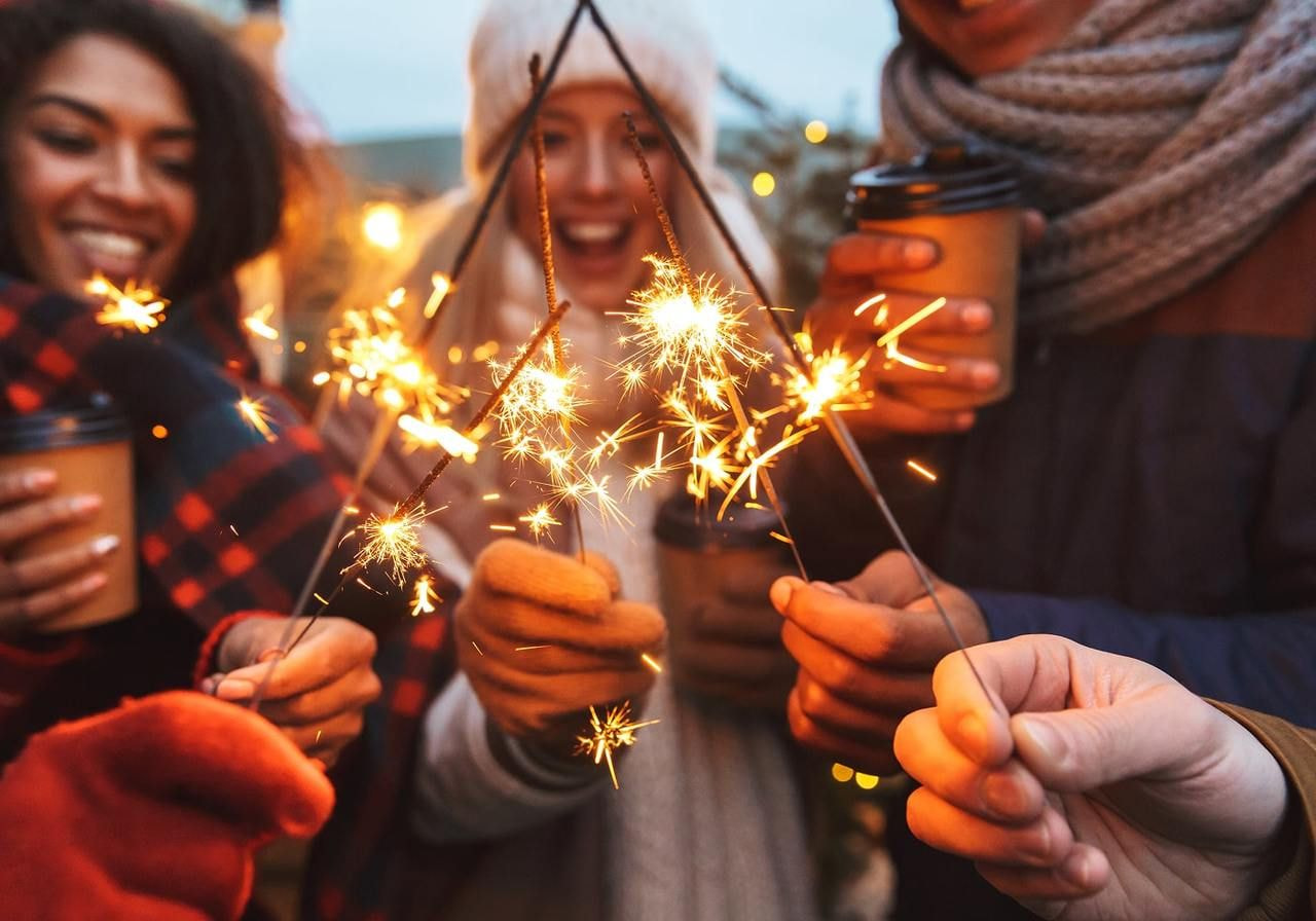 A joyful group of people smiling while holding sparklers, creating a festive atmosphere.