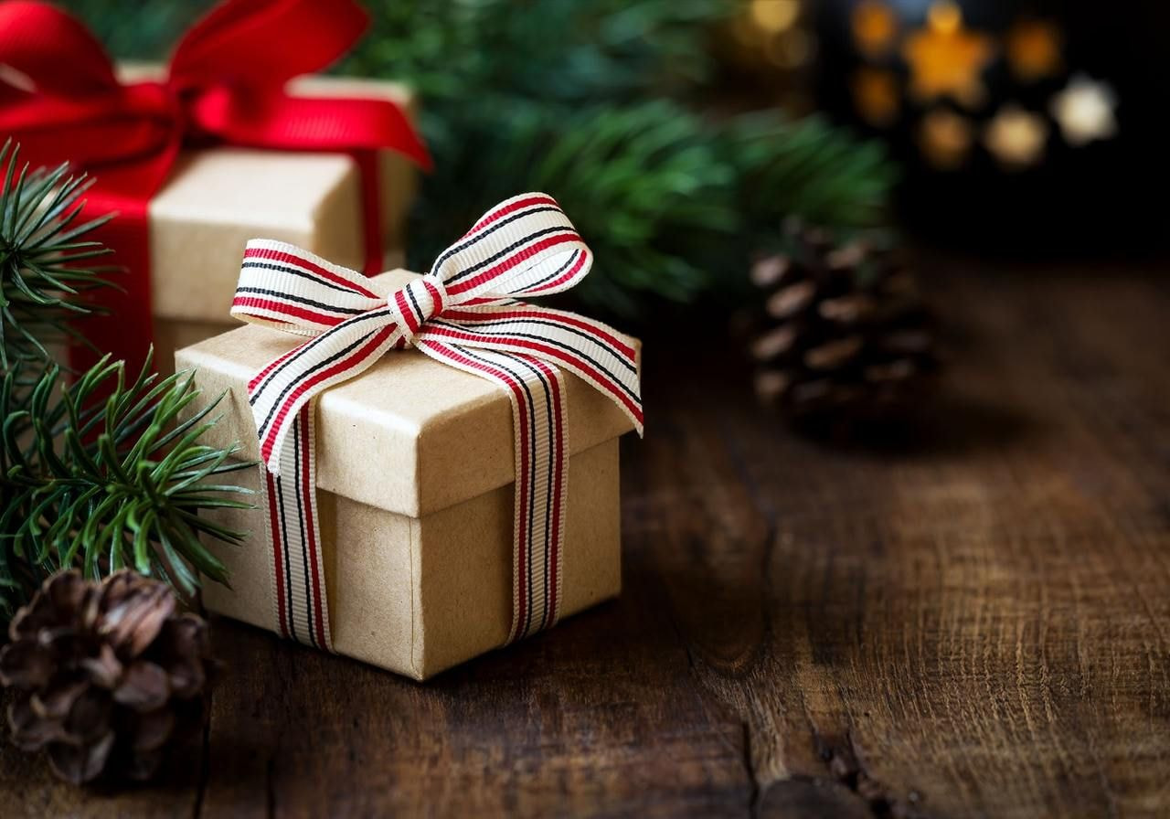 A wooden table adorned with wrapped gifts, pine cones, and festive Christmas decorations.