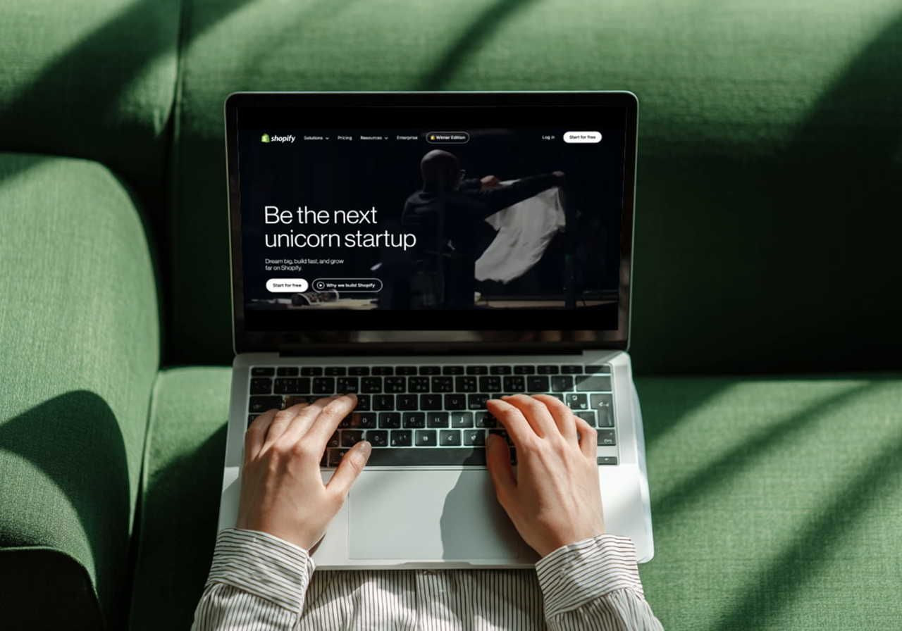 A person using a laptop with Shopify’s homepage on the screen.