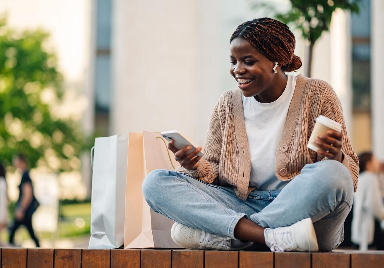 A young woman is using her smartphone while sitting in a bustling city environment.