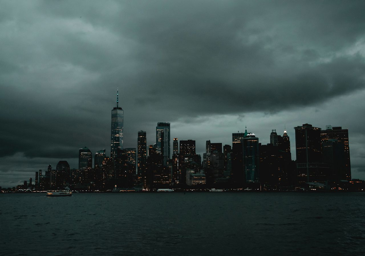 Dark, overcast sky over a city skyline at dusk.