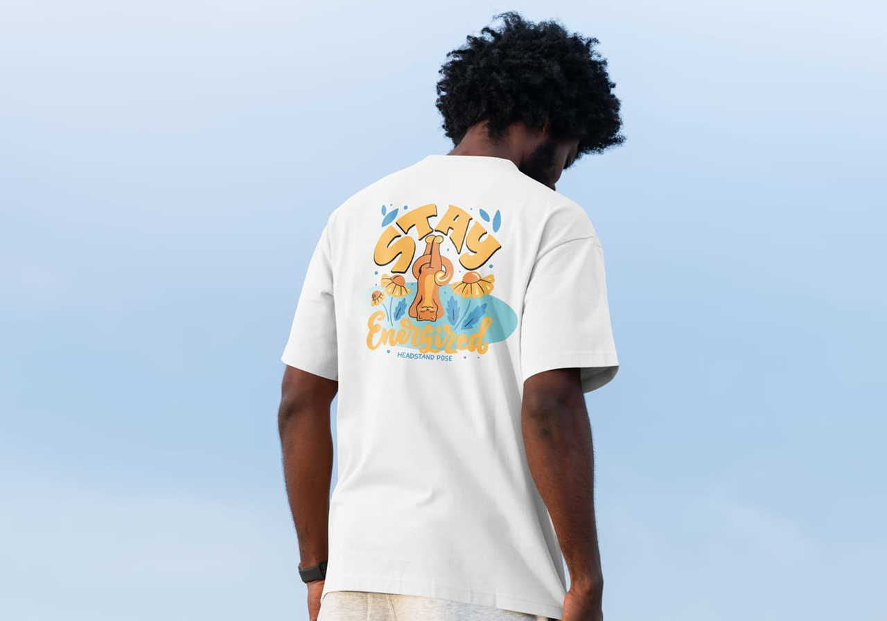 Back shot of a man with curly hair wearing a white t-shirt. The shirt has an illustrated cat doing yoga design, saying "Stay Energized".