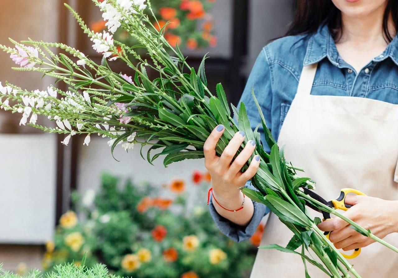 A woman smiling while holding a vibrant bouquet of flowers in her hands.