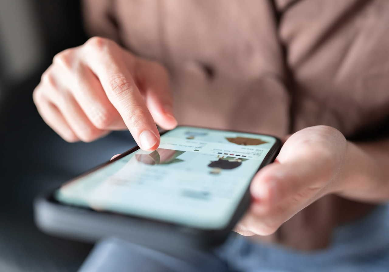 A person using a smartphone to browse an app or website, searching for tips on social media marketing for eCommerce.
