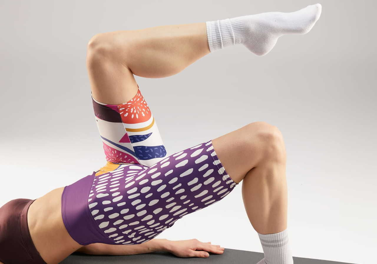 A person performing a bridge exercise while wearing colorful, all-over print patterned shorts.