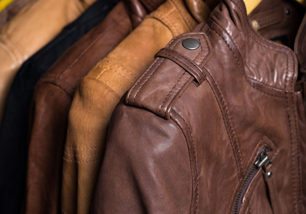 Close-up of brown leather jackets on hangers, emphasizing texture and detail.