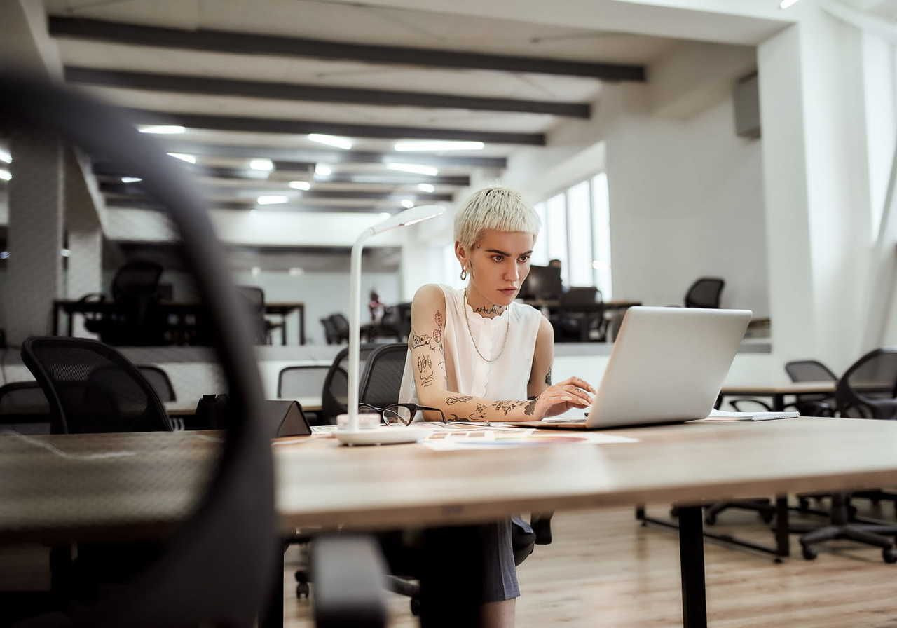 A thoughtful woman is focused on a laptop screen, in an office sitting, searching for how to make money from home.