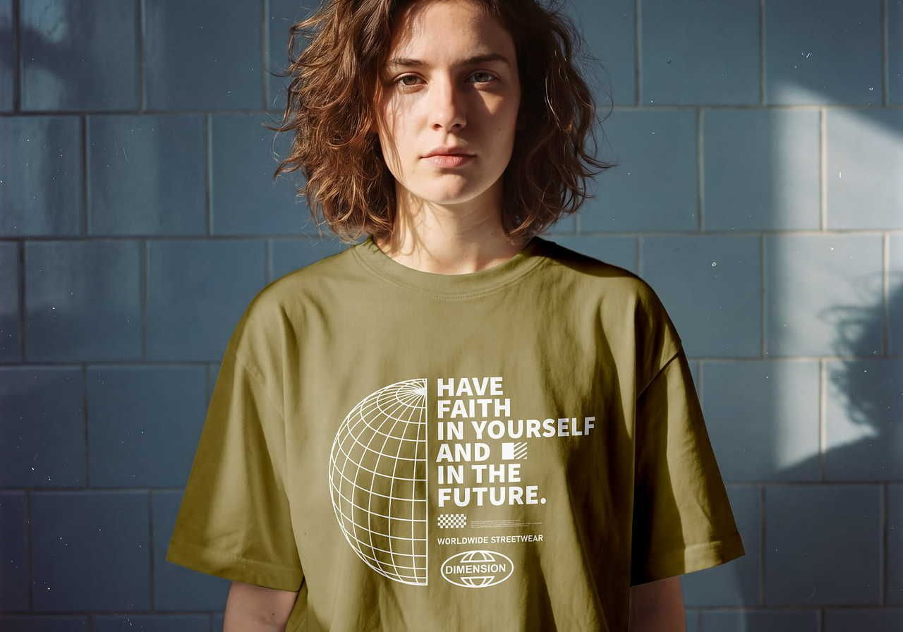 A woman with curly hair wearing an olive green "HAVE FAITH IN YOURSELF AND IN THE FUTURE" t-shirt alongside a graphic of a globe.
