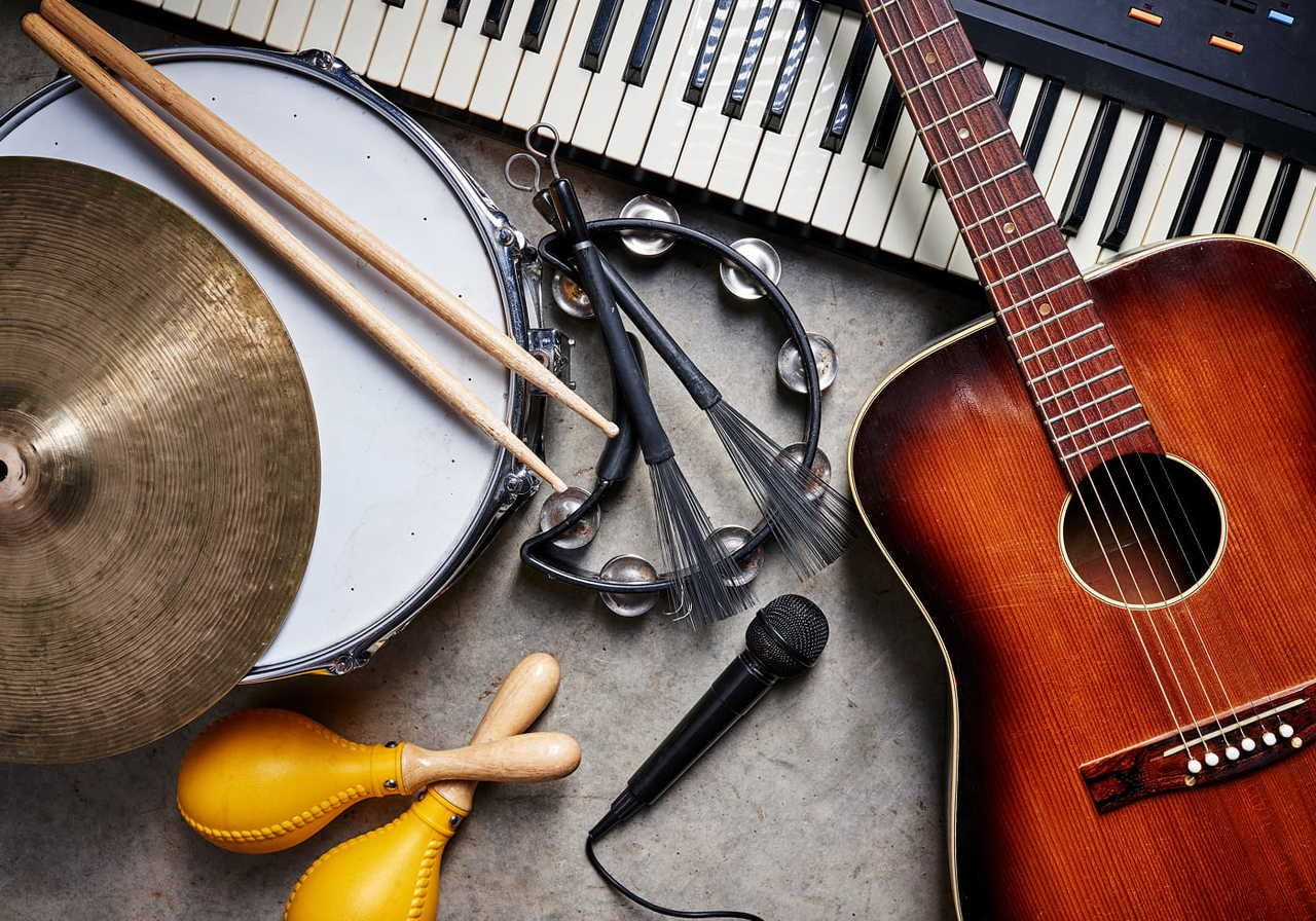 A collection of musical instruments, including a guitar, keyboard, cymbal, drumsticks, tambourine, maracas, and a microphone.