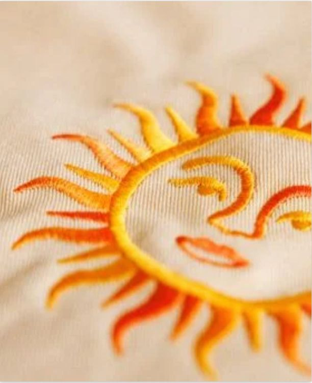 a sun and face embroidered on fabric