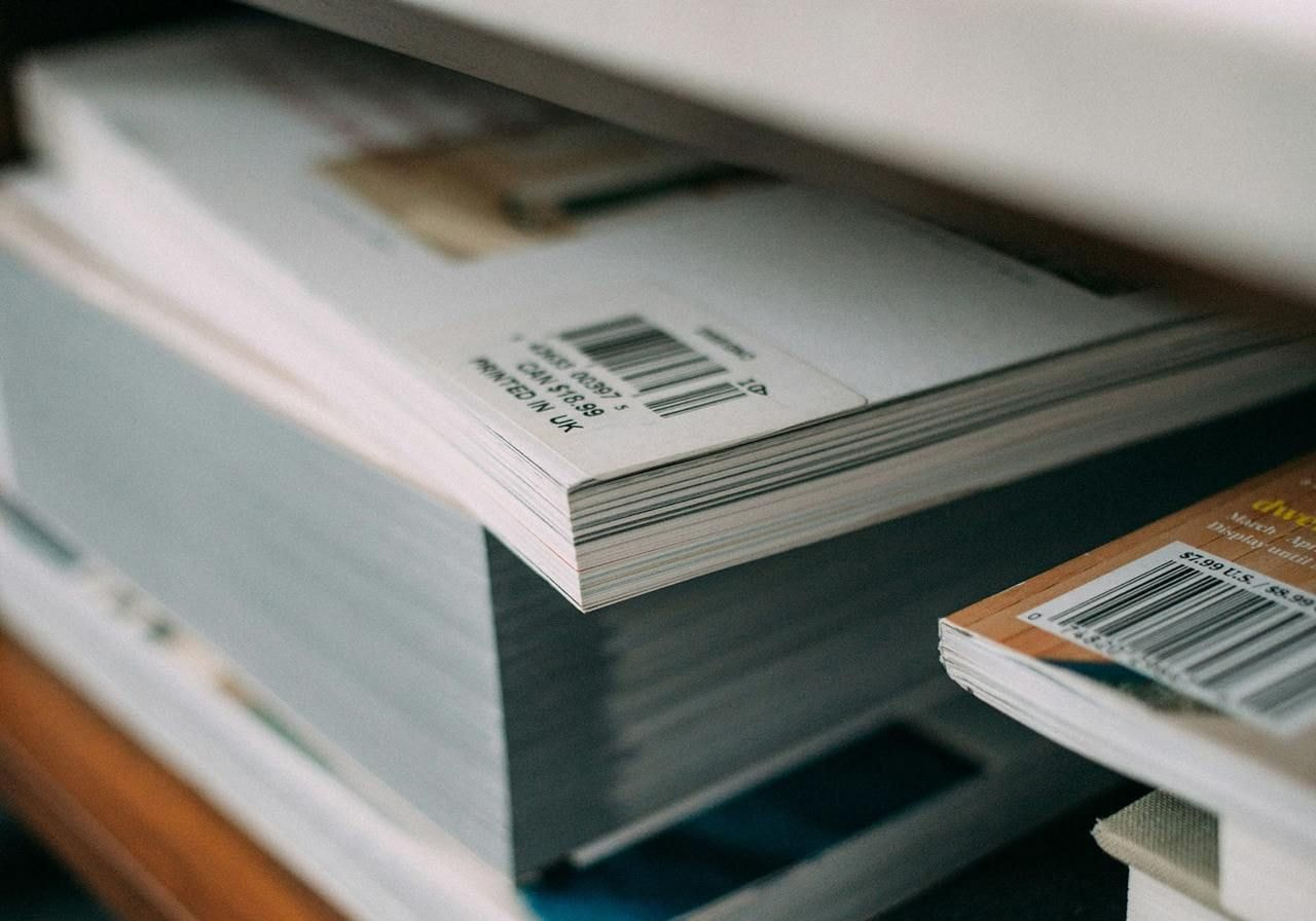 A stack of various books neatly arranged on a wooden shelf.