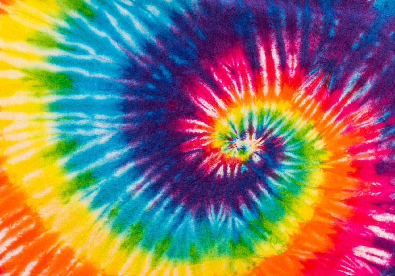 Vibrant tie-dye spiral with bright colors like blue, red, yellow, and green, creating a dynamic, energetic pattern radiating from the center.