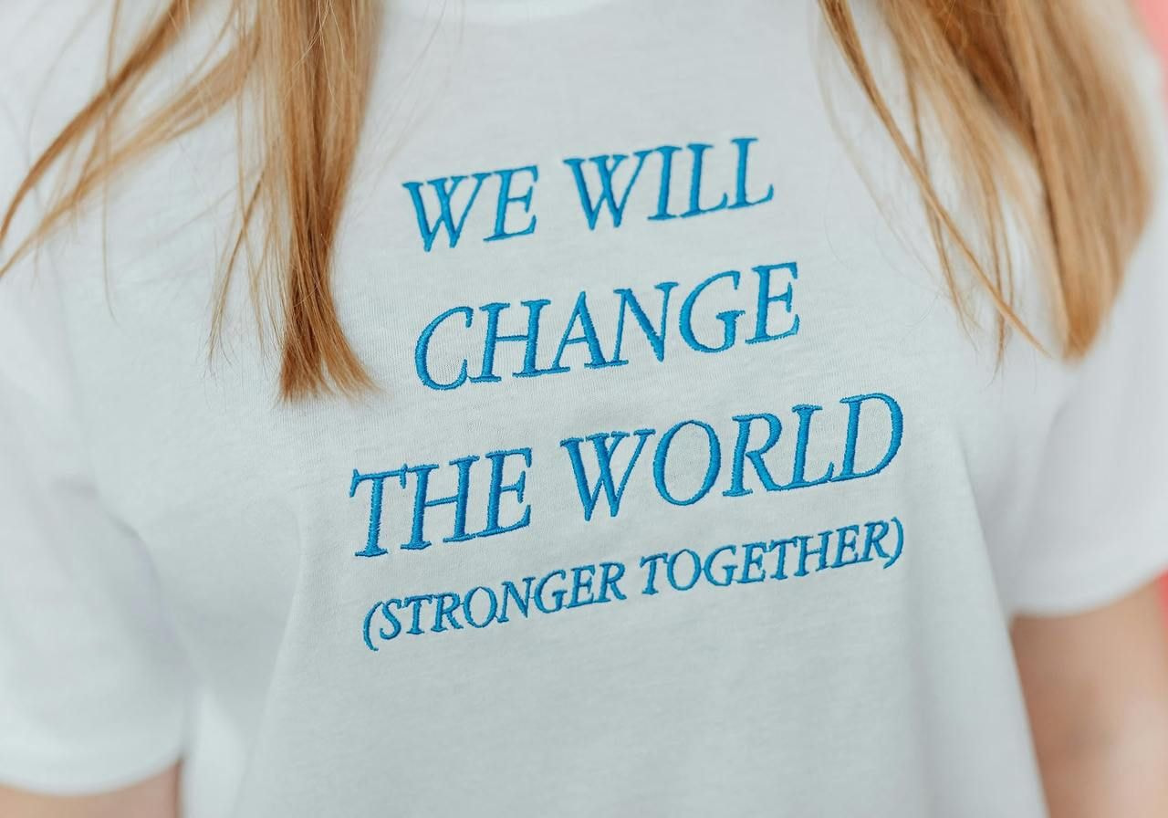 T-shirt featuring the phrase "We will change the world stronger together" in bold, inspiring typography.