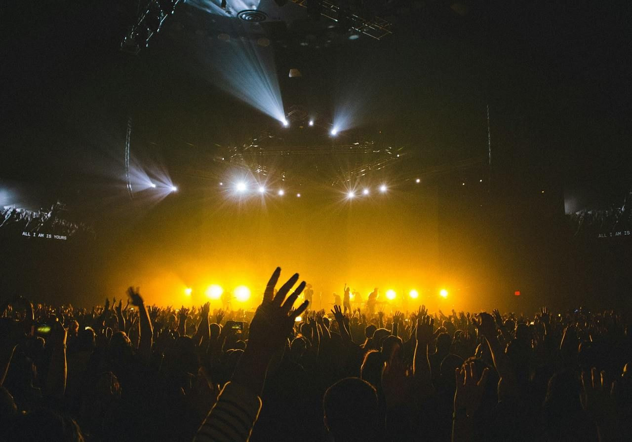 A lively concert crowd with hands raised, enjoying the music and atmosphere.