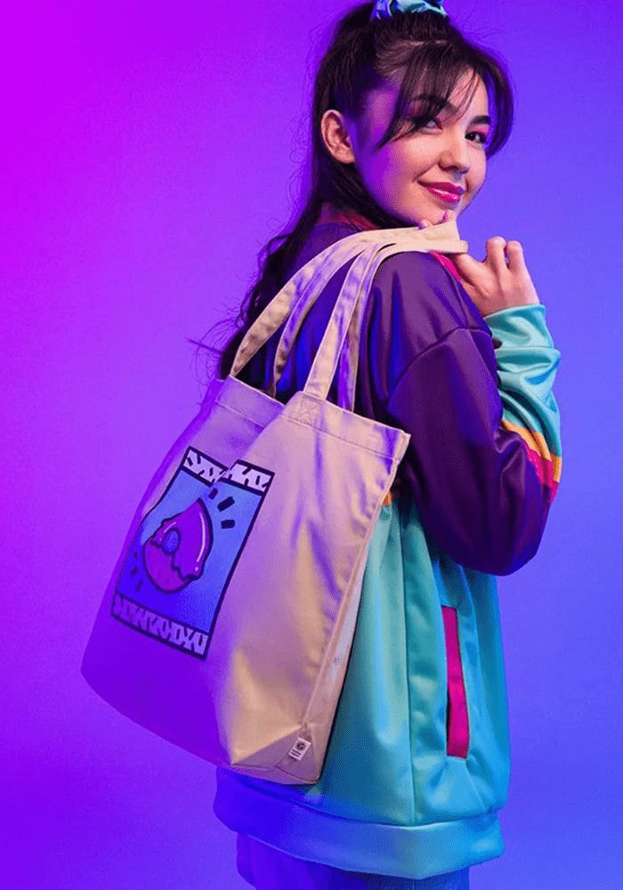 A girl smiles while holding a bag featuring a colorful cartoon character design.