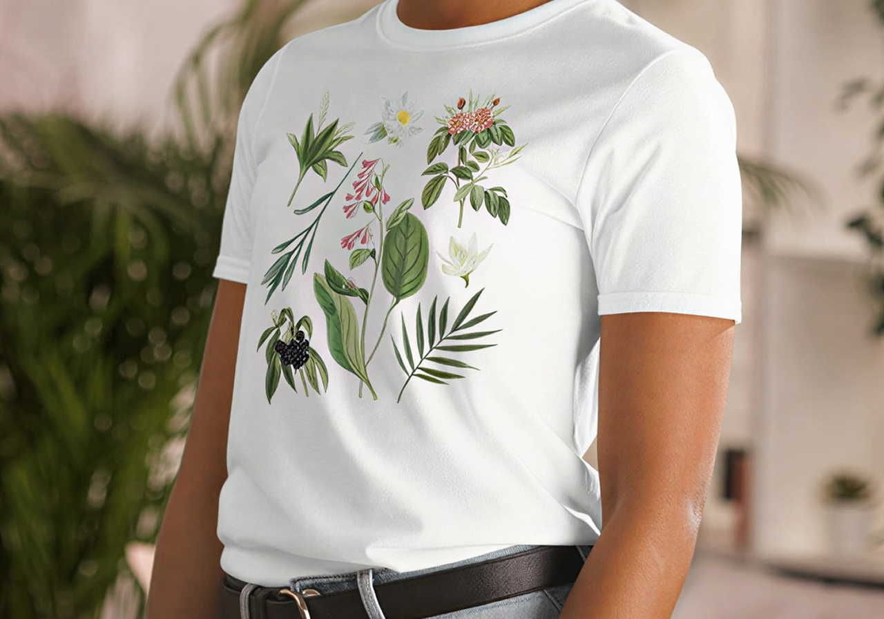 Person wearing a white t-shirt with botanical illustrations, featuring various green leaves and colorful flowers.