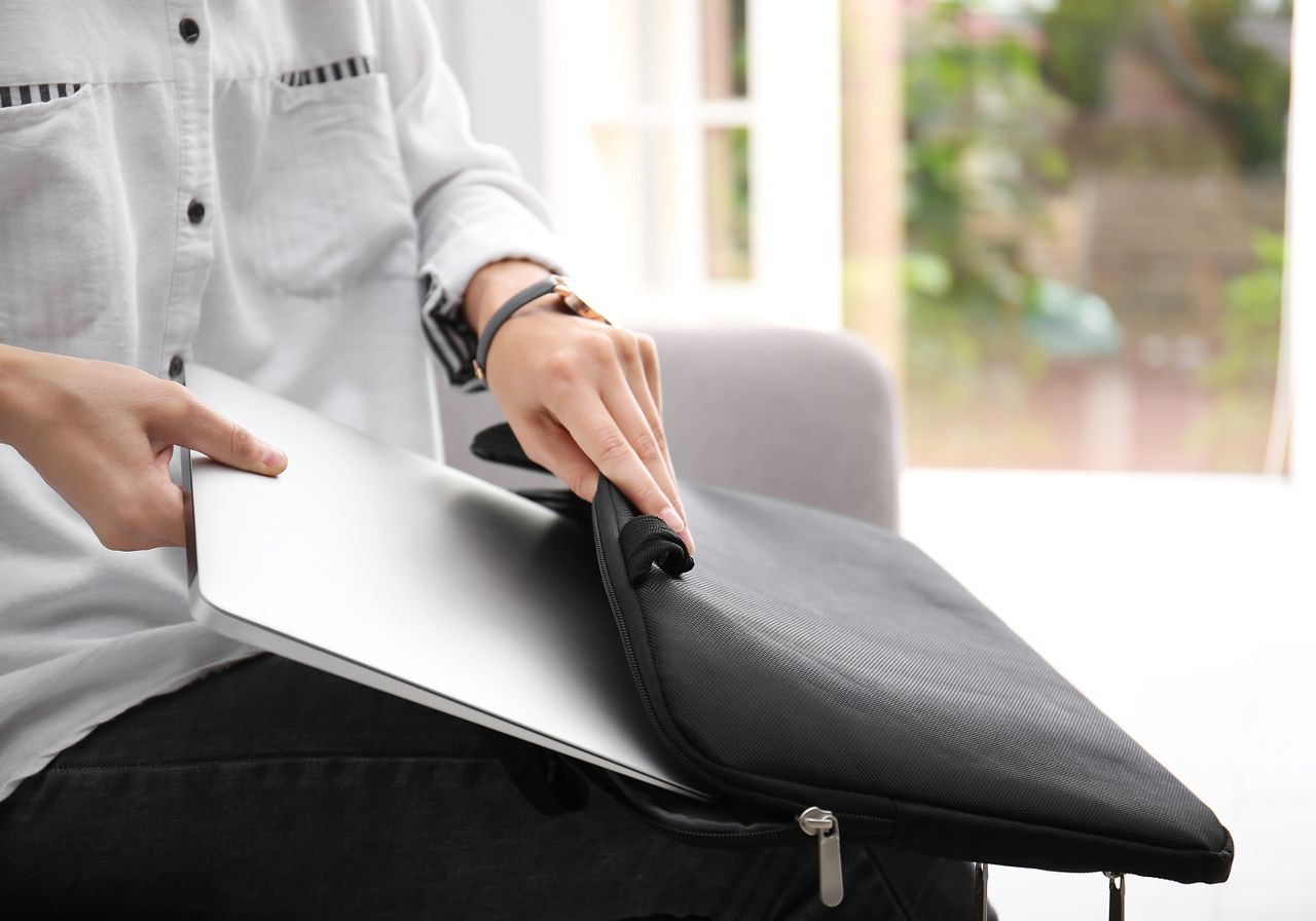 A person is putting their laptop in a laptop case