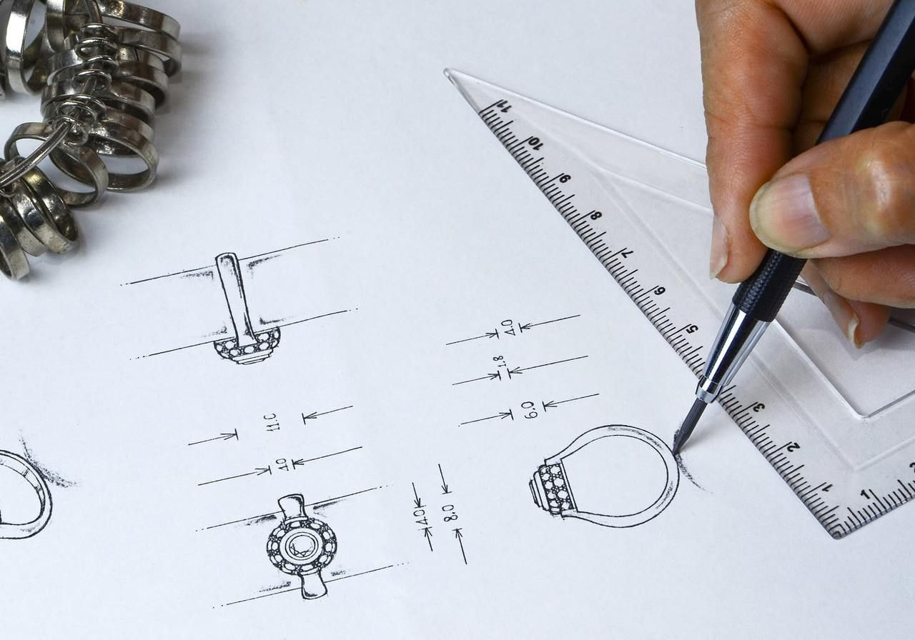 A person uses a ruler to draw on a piece of paper, focusing intently on their work.