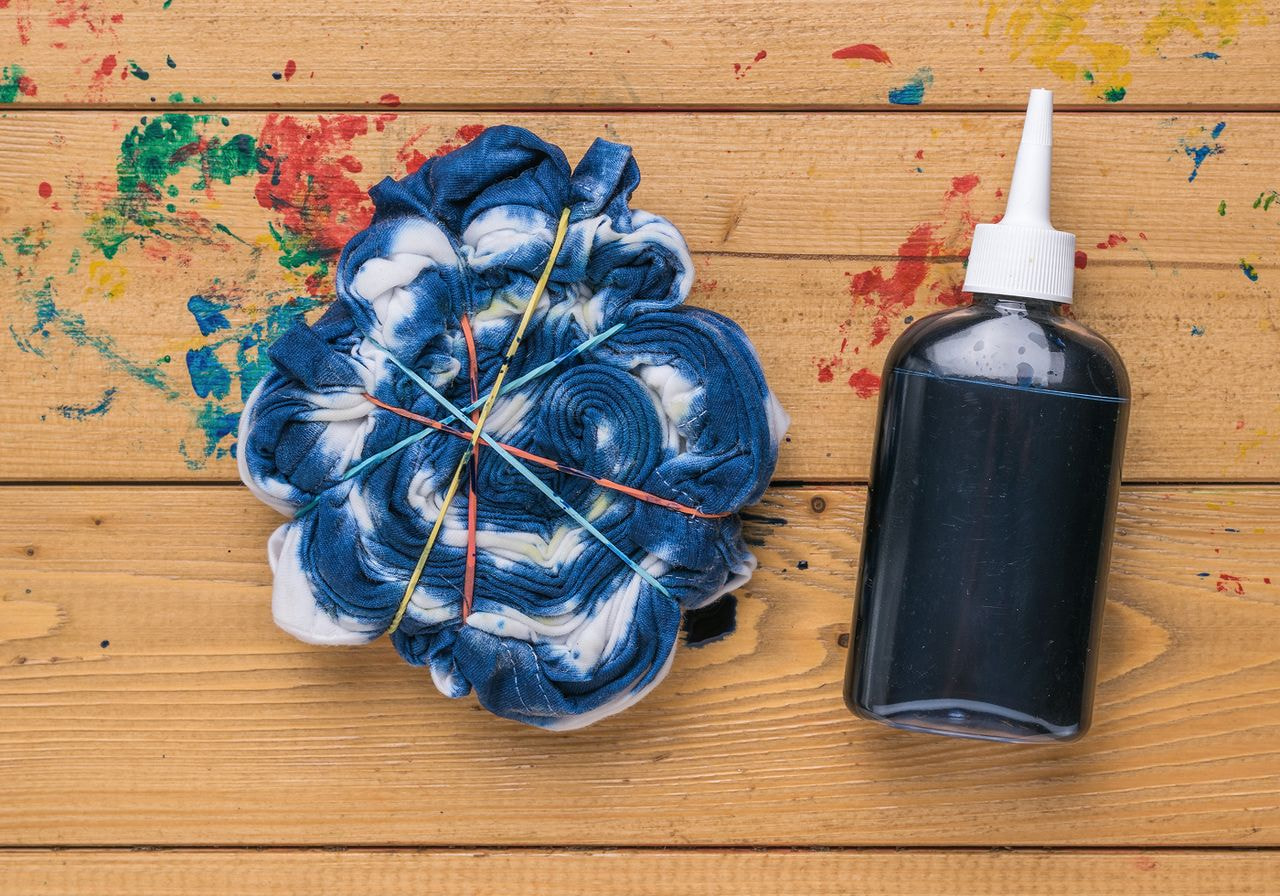 A tie-dye project on a wooden surface with splattered paint.