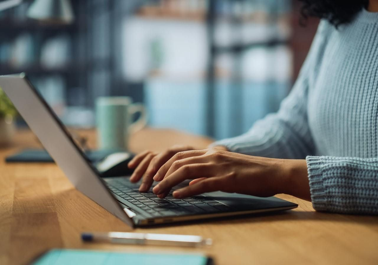 A woman is typing on a laptop.