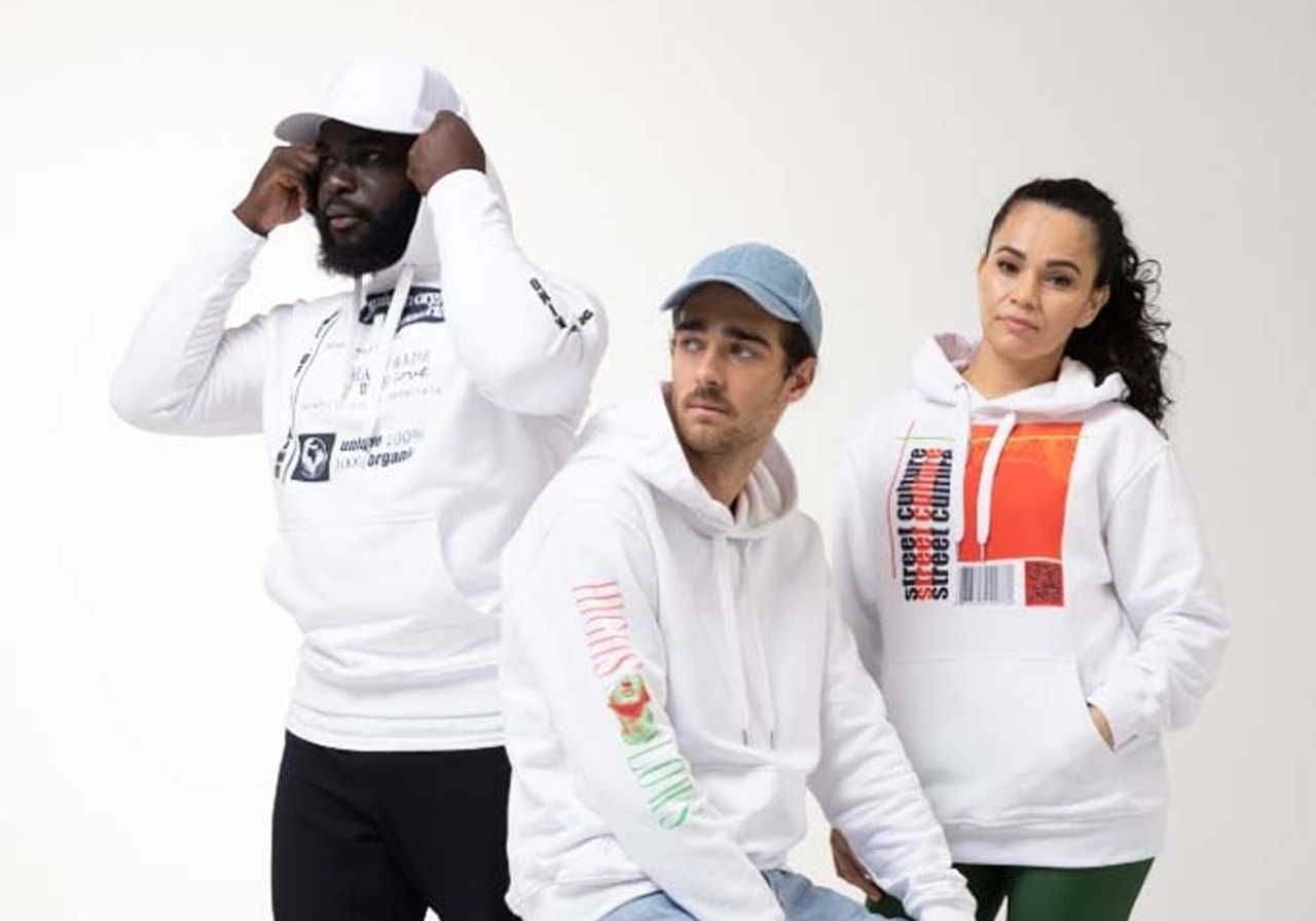 A group of three people wearing casual streetwear, including hoodies and caps, posing against a plain background.