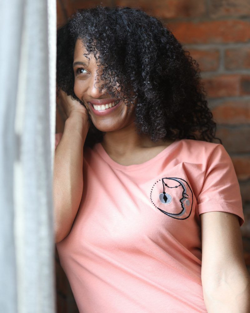 Mulher usando camiseta com impressão DTG sorrindo próxima a janela