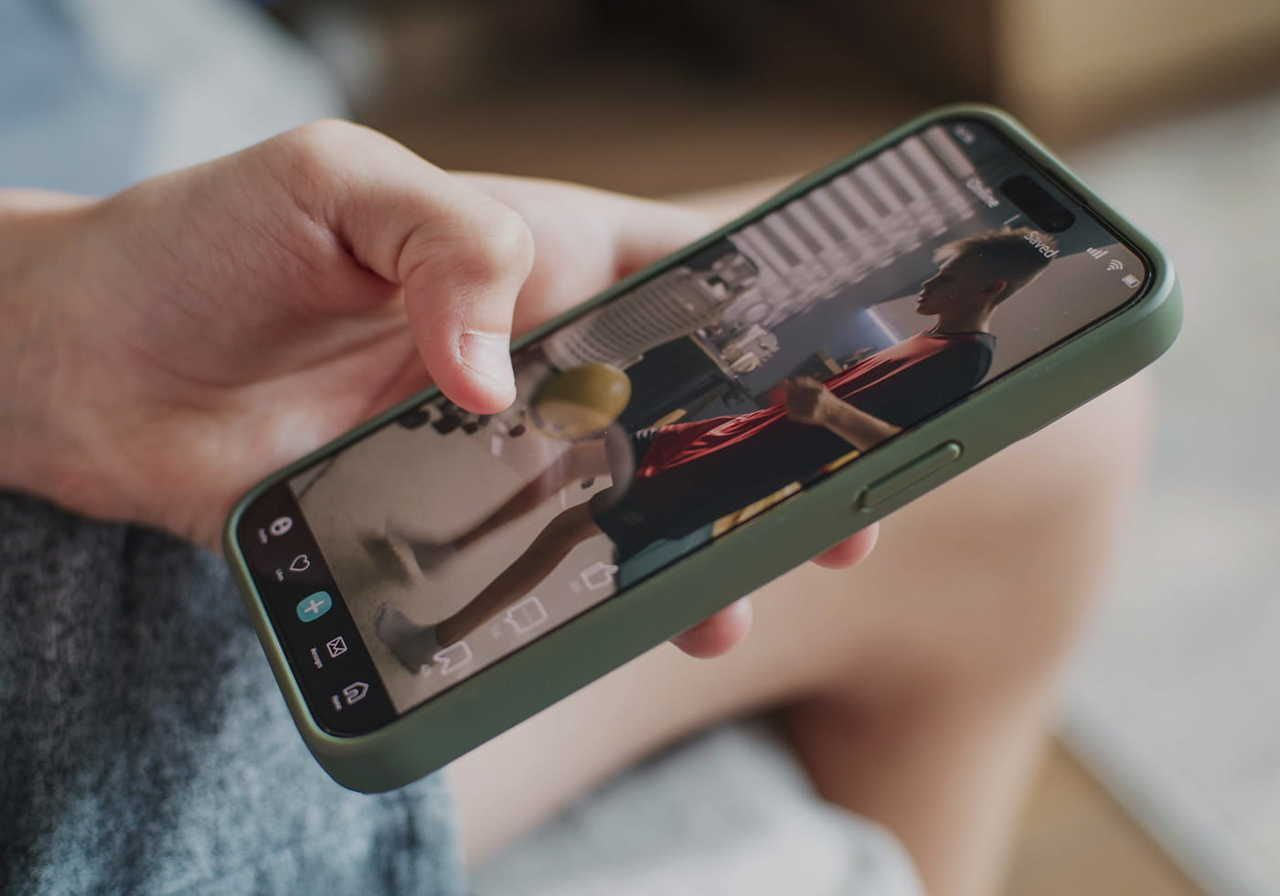 A person holding a smartphone displaying an image or video on the screen.