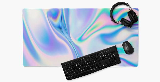Desk setup featuring a large iridescent mouse pad with a black keyboard, wireless mouse, and over-ear headphones on a white background.
