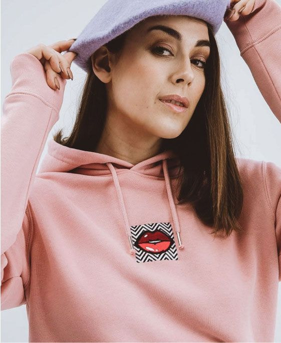 a woman wearing a pink hoodie and a hat