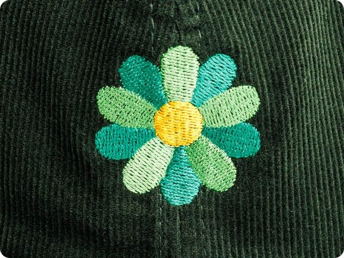 Green flat embroidered flower on dark green fabric
