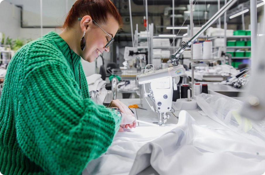 Print-on-demand production with worker sewing apparel on industrial machine in fulfillment center
