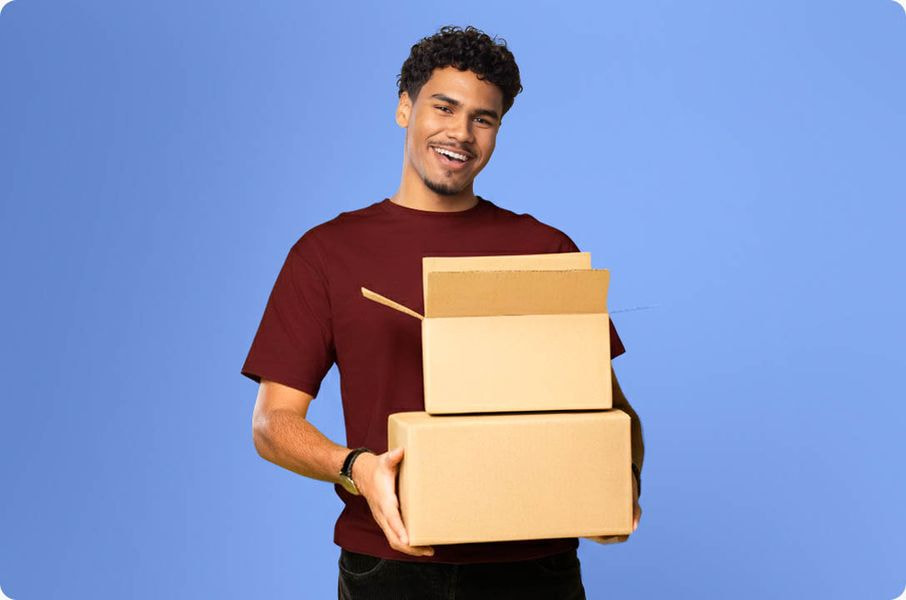 Smiling person carrying stacked shipping boxes, representing fast order fulfillment and delivery.