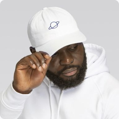 man in a white hoodie wearing a white cap with a planet embroidered on it 