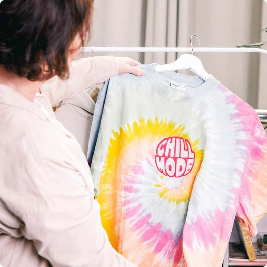 a woman holding a tie dye shirt